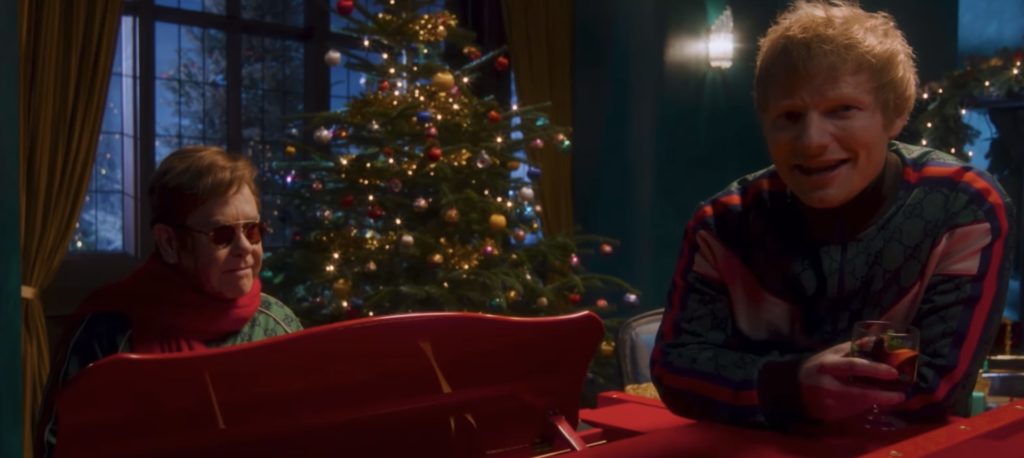 Their teaser video pays homage to the film, with Sheeran knocking on John's door with a stack of note cards that read, "Hello. Last Christmas, I received a call from my mate Elton John, and he told me we should do a 'Christmas Song,' And I replied, 'Yeah. Maybe in 2022.' But I actually wrote the chorus that day, and here we are. Our Christmas song 'Merry Christmas' is out this Friday. Go pre-order or pre-save it now. It has sleigh bells. A lot of them...."