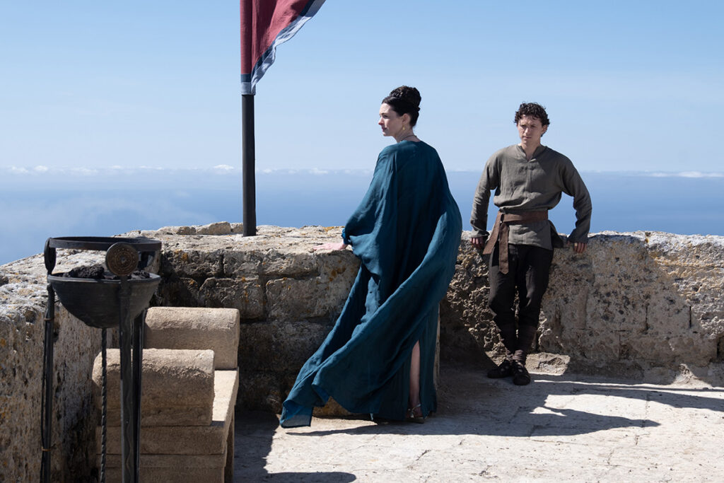 Let me say the quiet part loudly: Christopher Nolan did not make a swords-and-sandals adventure. He made a war film wearing a myth as a mask, and it may be the most punishing, beautiful thing he has ever put on a screen. The Odyssey is his thirteenth feature, the first narrative film in history shot entirely on IMAX film, and already the biggest global launch of his career — an instant awards frontrunner that had the industry roaring from its first CinemaCon footage onward, in a year that suddenly has very little competition. Coming off Oppenheimer, Nolan has essentially made a companion piece in bronze: another story about a brilliant man whose single clever idea unleashes a horror the world cannot put back in the box. If Oppenheimer gave us the father of the atomic bomb, The Odyssey gives us his Bronze Age ancestor.