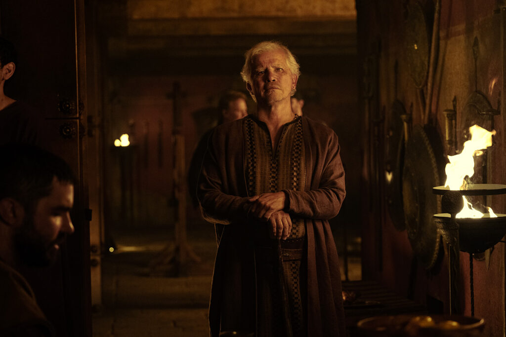 Let me say the quiet part loudly: Christopher Nolan did not make a swords-and-sandals adventure. He made a war film wearing a myth as a mask, and it may be the most punishing, beautiful thing he has ever put on a screen. The Odyssey is his thirteenth feature, the first narrative film in history shot entirely on IMAX film, and already the biggest global launch of his career — an instant awards frontrunner that had the industry roaring from its first CinemaCon footage onward, in a year that suddenly has very little competition. Coming off Oppenheimer, Nolan has essentially made a companion piece in bronze: another story about a brilliant man whose single clever idea unleashes a horror the world cannot put back in the box. If Oppenheimer gave us the father of the atomic bomb, The Odyssey gives us his Bronze Age ancestor.